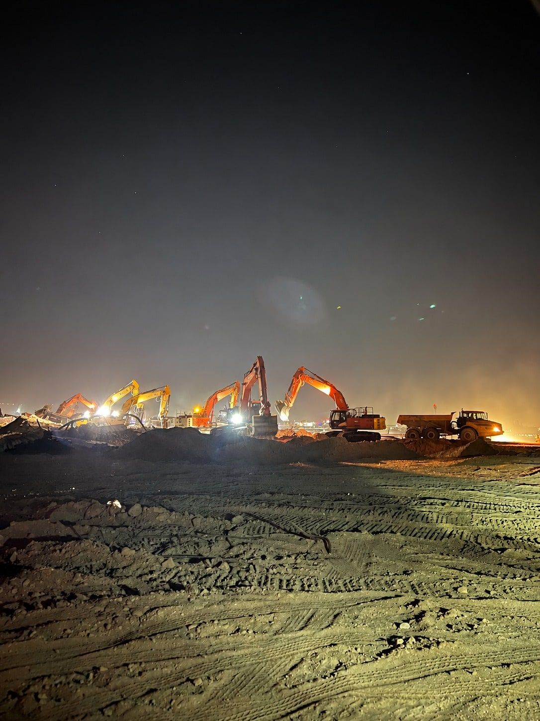 Excavators working at night on the cleared refinery site