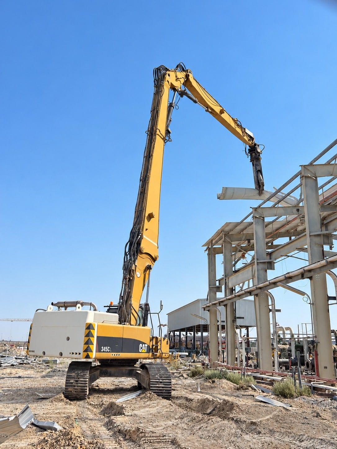 High-reach excavator with shear removing a steel pipe rack