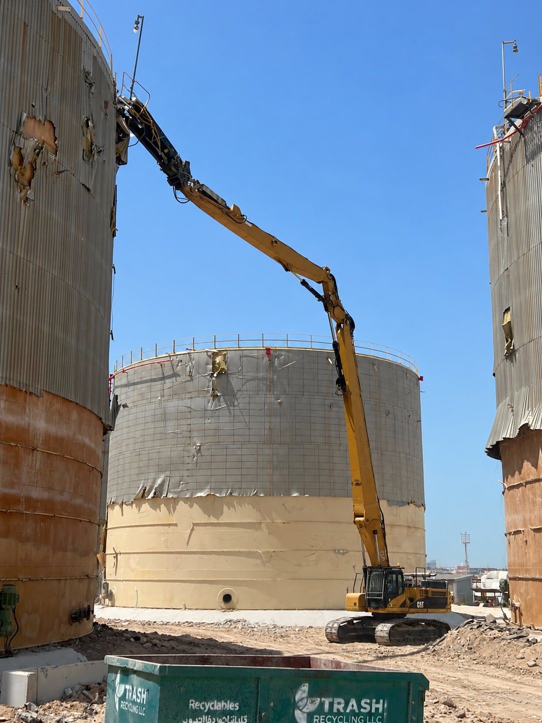 Long-reach excavator dismantling insulated storage tanks