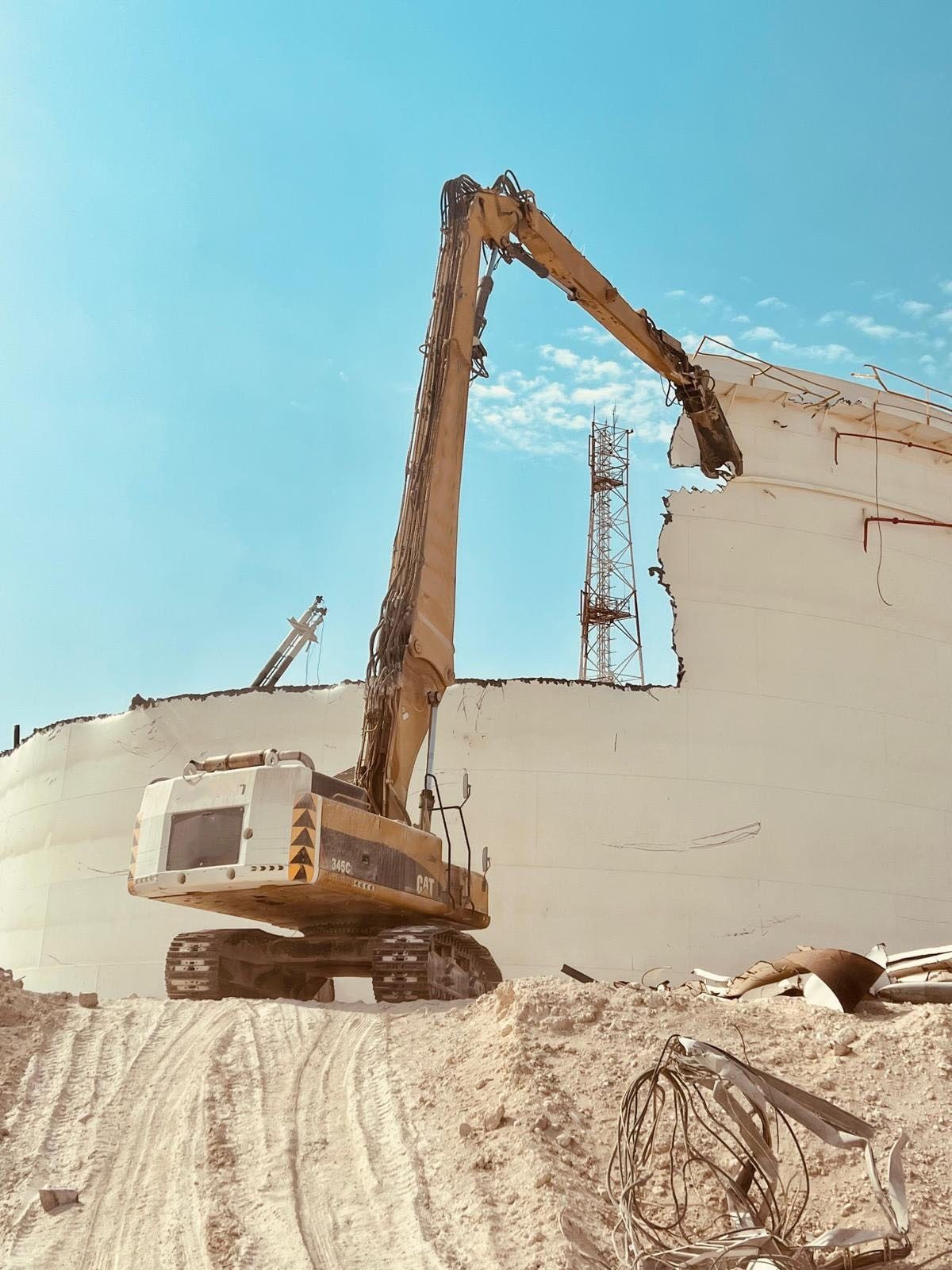 High-reach excavator cutting the roof edge of a storage tank
